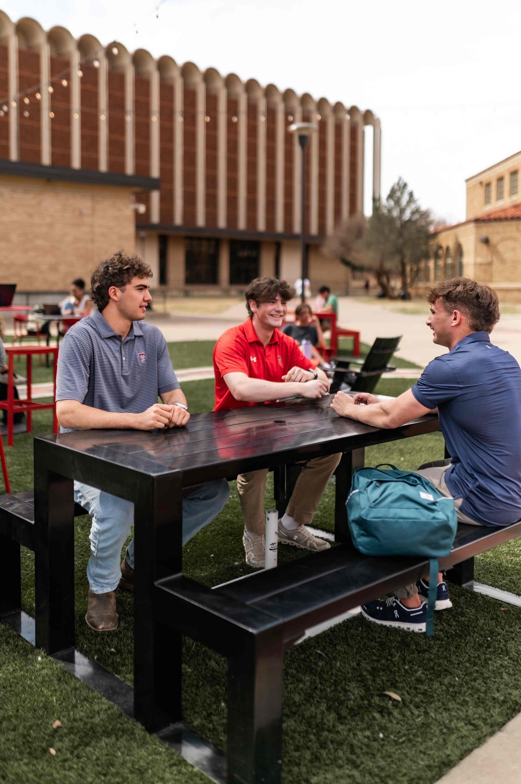 three students sitting at outdoor table near troubadour in lubbock tx scaled